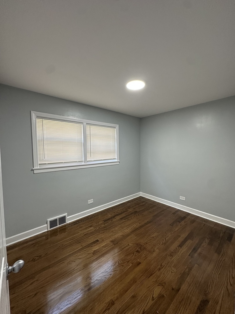 8232 Keating Avenue, Unit 1 Skokie, IL 60076 - Photo 17 of 21 a view of an empty room with wooden floor and a window