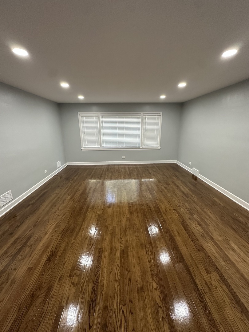 8232 Keating Avenue, Unit 1 Skokie, IL 60076 - Photo 4 of 21 an empty room with wooden floor and windows
