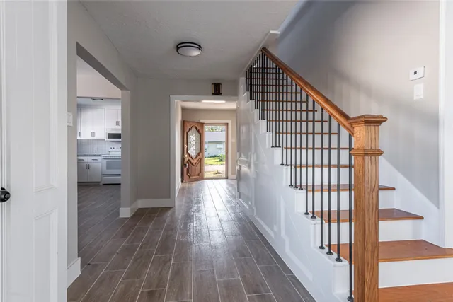 a view of a hallway with wooden floor and a bathroom