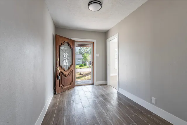 a view of a hallway with wooden floor and a window