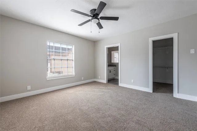 an empty room with chandelier fan and windows