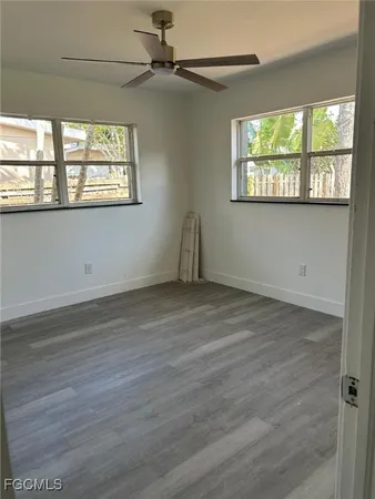 an empty room with wooden floor fan and windows