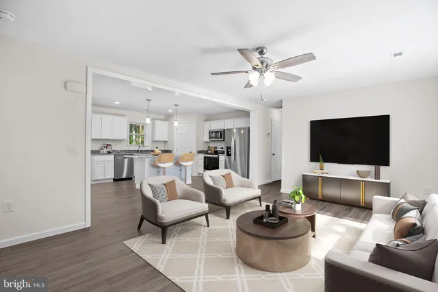 a living room with furniture a flat screen tv and kitchen view