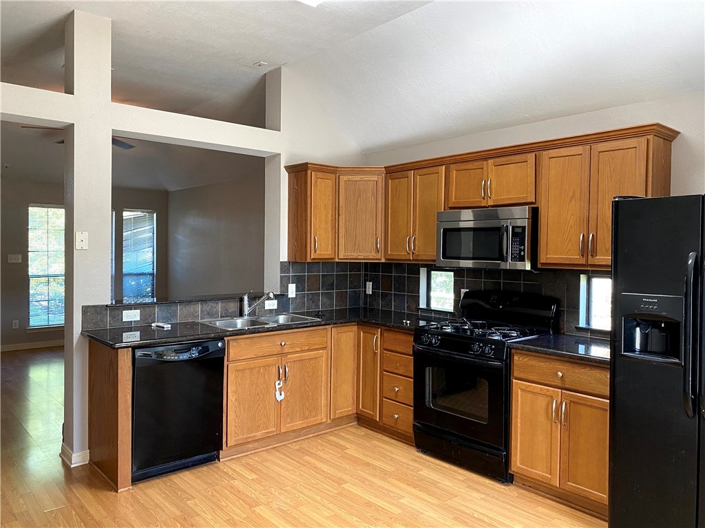 2018 Snowy Brook Trail Bryan, TX 77807 - Photo 6 of 9 a kitchen with stainless steel appliances granite countertop a stove top oven a sink dishwasher and a refrigerator with wooden floor