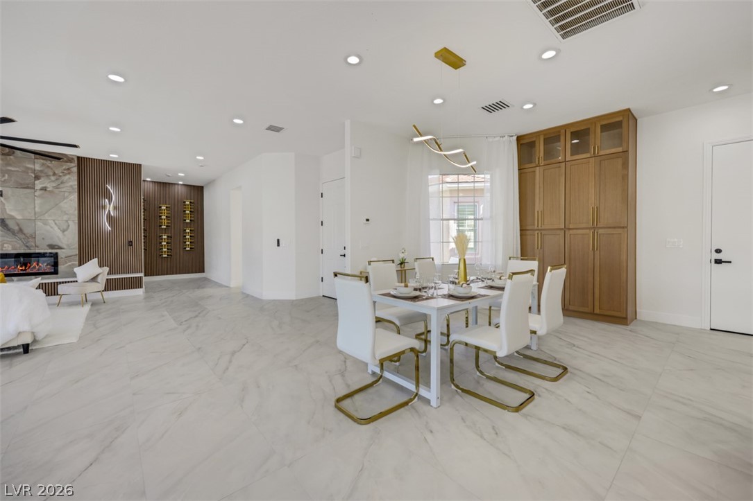 5015 Rivedro Street Las Vegas, NV 89135 - Photo 91 of 91 An open floorplan seamlessly connects a chic dining area with a modern living space featuring a linear fireplace.