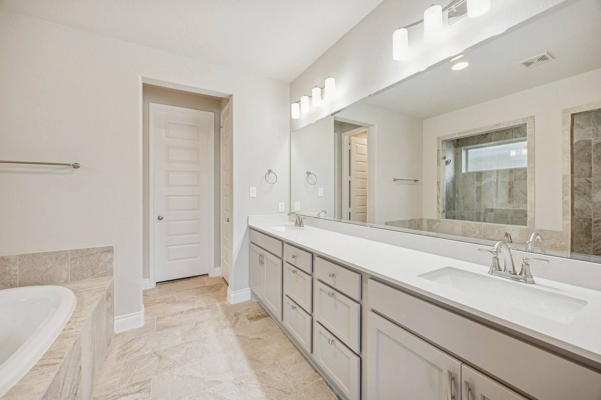 28706 Casen Ranch Lane Fulshear, TX 77441 - Photo 14 of 31 The primary ensuite is a masterpiece of design, featuring a large double vanity with Quartz countertops and contemporary fixtures. Sleek tile flooring and elegant lighting enhance the sophisticated atmosphere.