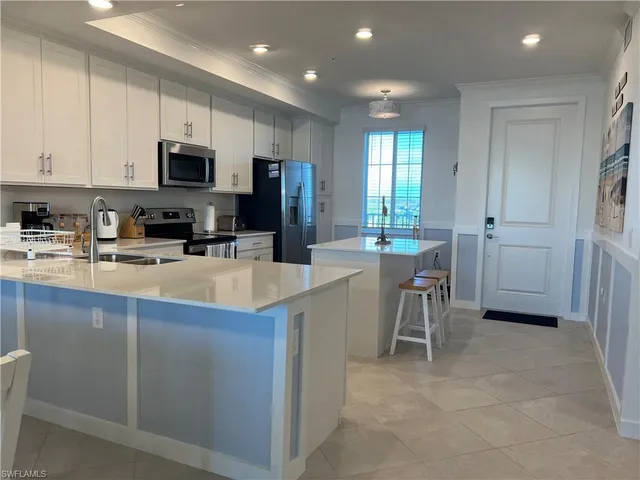 a kitchen with stainless steel appliances a microwave a sink a stove a table and chairs
