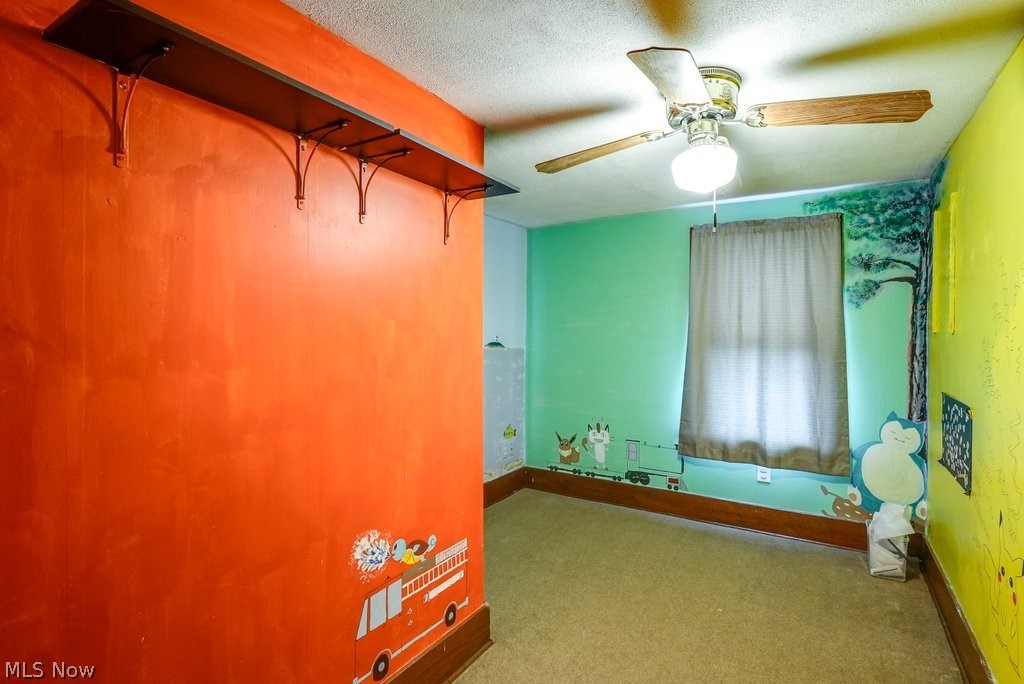 851 Ranney Street Akron, OH 44310 - Photo 24 of 30 Spare room featuring a textured ceiling, dark colored carpet, and ceiling fan