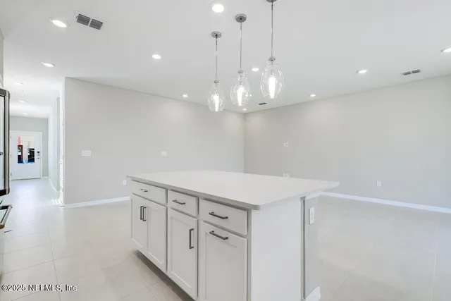 a kitchen with white cabinets and chandelier