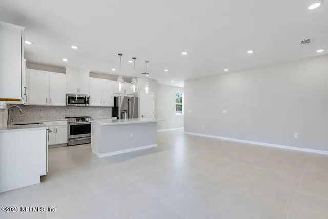 a view of kitchen with kitchen island stainless steel appliances cabinets and stove top oven
