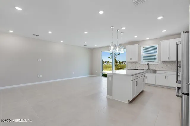 a large kitchen with granite countertop a sink and white cabinets