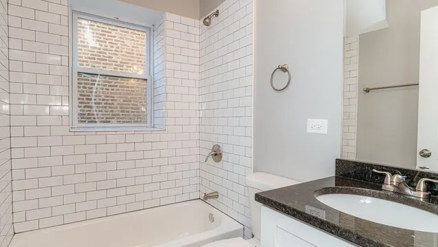 a bathroom with a granite countertop sink a mirror and a bathtub