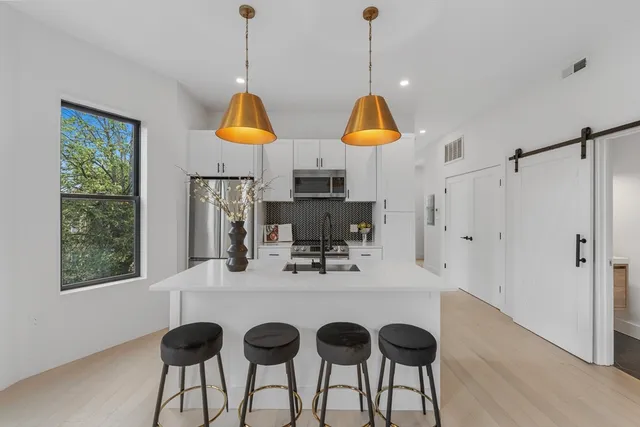 a kitchen with stainless steel appliances granite countertop a dining table chairs and chandelier