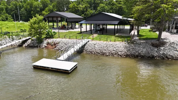 a view of a house with pool and a lawn chairs under an umbrella