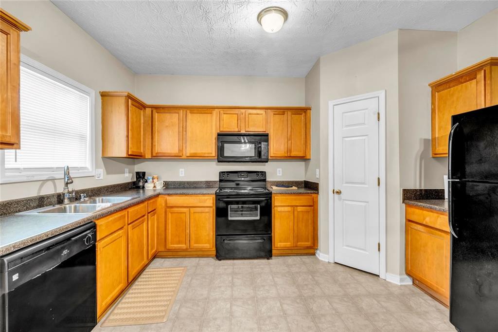 1246 Adcox Square Stone Mountain, GA 30088 - Photo 11 of 22 a kitchen with stainless steel appliances granite countertop a stove top oven a refrigerator and a sink with granite countertops