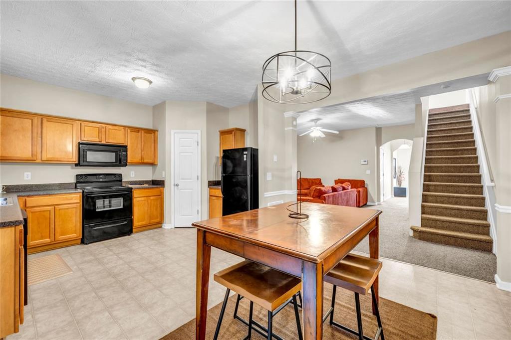 1246 Adcox Square Stone Mountain, GA 30088 - Photo 12 of 22 a kitchen with stainless steel appliances kitchen island granite countertop a table chairs and a refrigerator