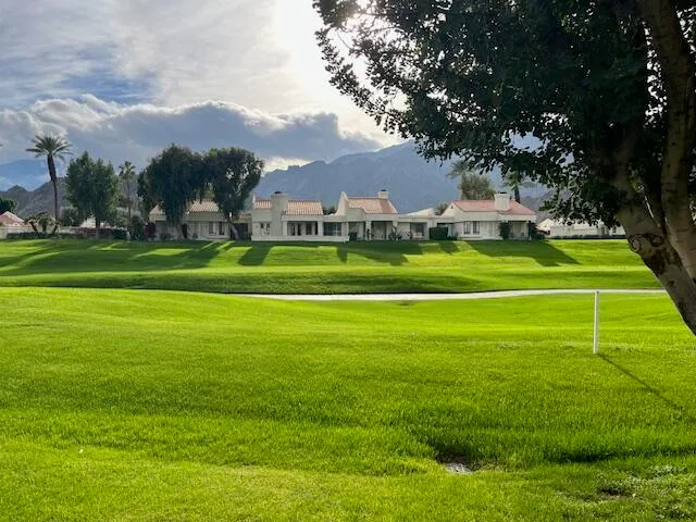 a front view of a house with a big yard and trees