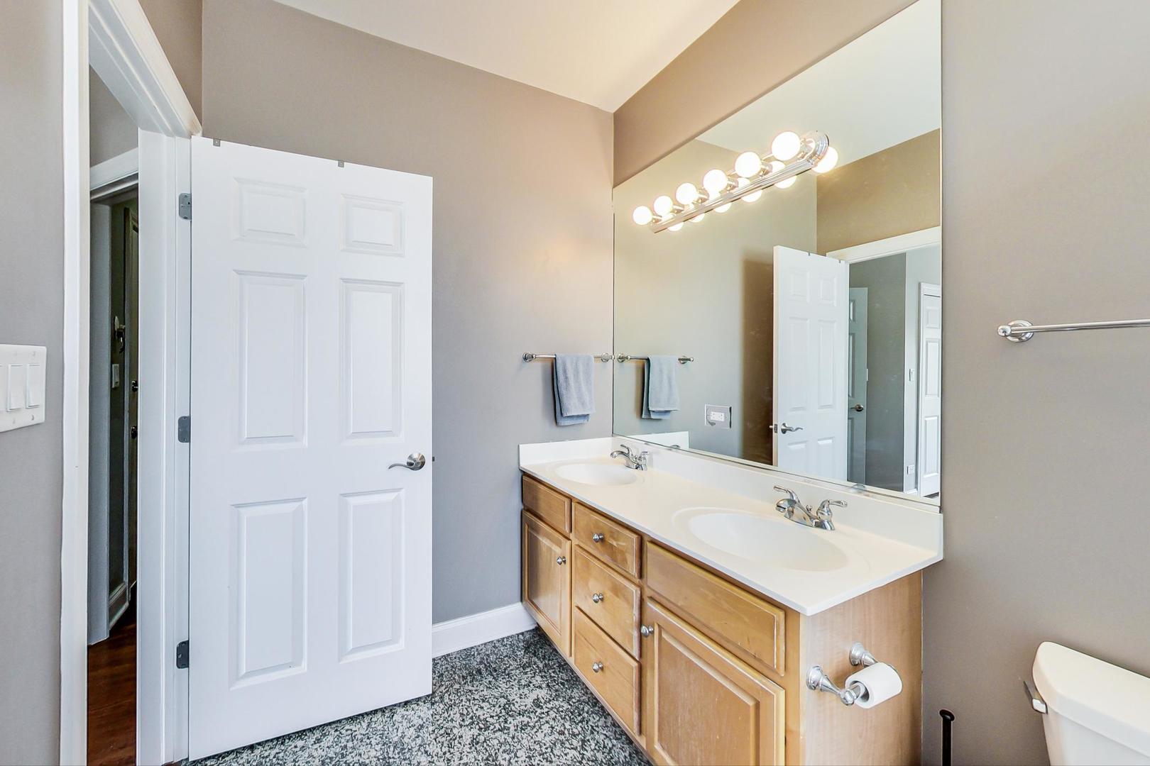 1033 West Taylor Street, Unit 2E Chicago, IL 60607 - Photo 12 of 20 a bathroom with a double vanity sink a mirror and a bathtub