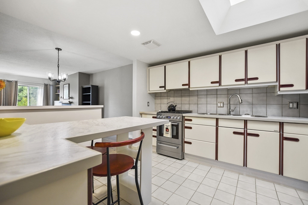 431 Place Lane, Unit 431 Woburn, MA 01801 - Photo 2 of 38 a kitchen with a dining table chairs and white cabinets