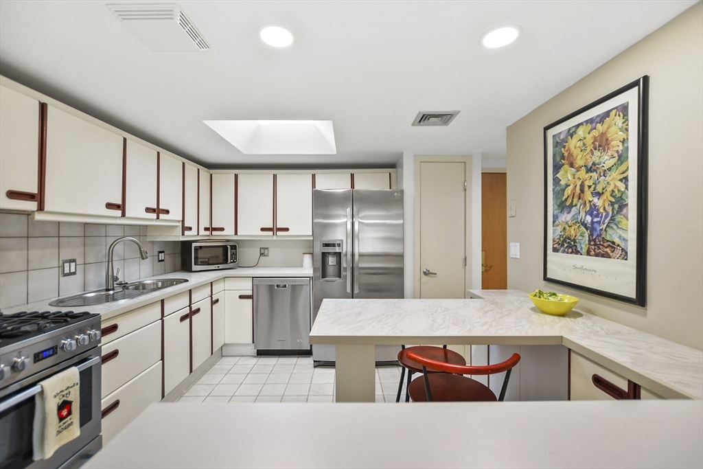 431 Place Lane, Unit 431 Woburn, MA 01801 - Photo 3 of 38 a kitchen with stainless steel appliances granite countertop a stove top oven a sink a dining table and chairs with wooden floor
