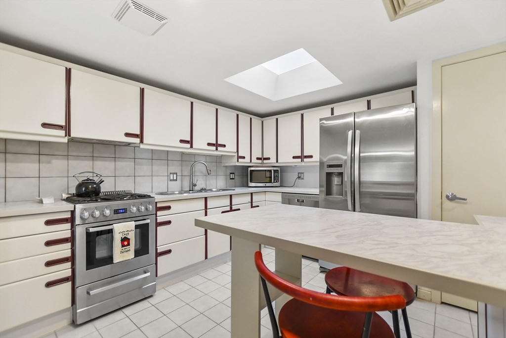 431 Place Lane, Unit 431 Woburn, MA 01801 - Photo 6 of 38 a kitchen with stainless steel appliances a stove a sink and white cabinets
