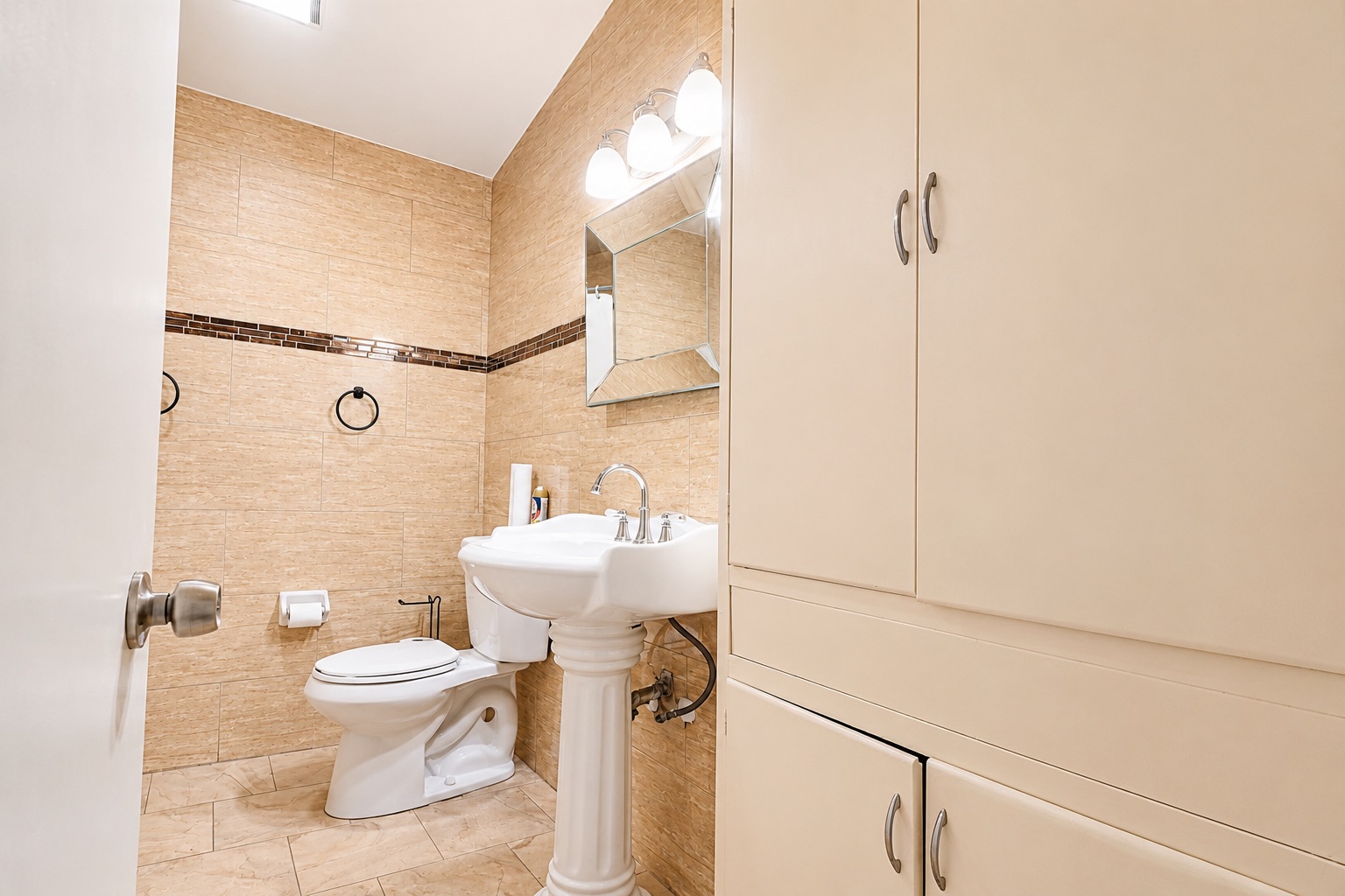 1508 Walnut Street Georgetown, TX 78626 - Photo 12 of 37 A neatly appointed bathroom features full tile walls and floor, complemented by a classic pedestal sink and ample cabinetry.