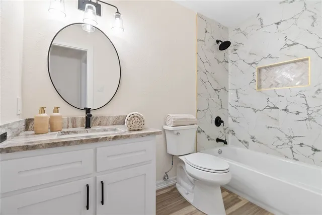 a bathroom with a granite countertop toilet a sink and a mirror
