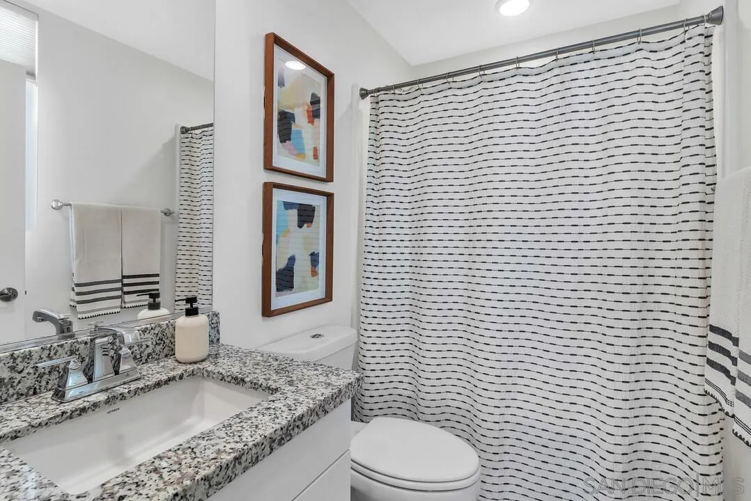 8844 Weston Road Santee, CA 92071 - Photo 18 of 48 a bathroom with a granite countertop toilet a sink a mirror and shower curtain