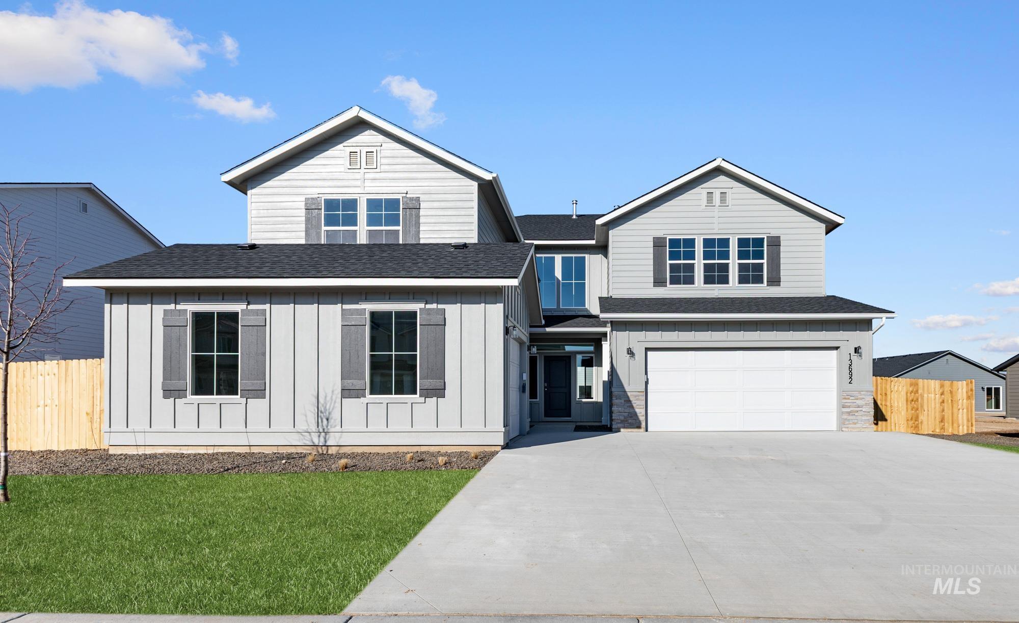 View of front of home with roof with shingles, an attached garage, driveway, and board and batten siding
