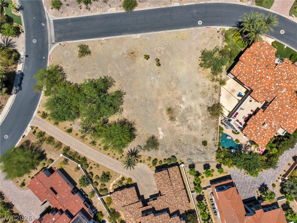 3 Rue Promenade Way Henderson, NV 89011 - Photo 10 of 26 A spacious lot awaits custom home development within a premier neighborhood, surrounded by mature landscaping and adjacent properties with pools.