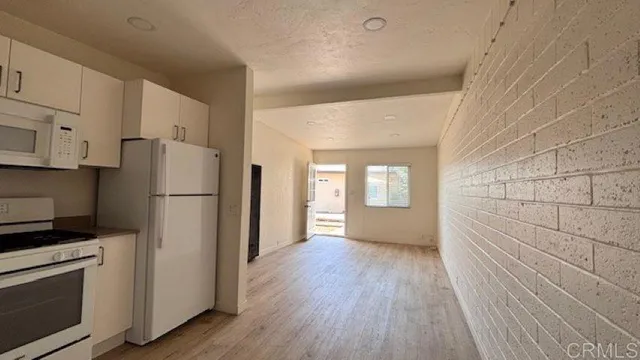 a view of kitchen with refrigerator cabinets and wooden floor