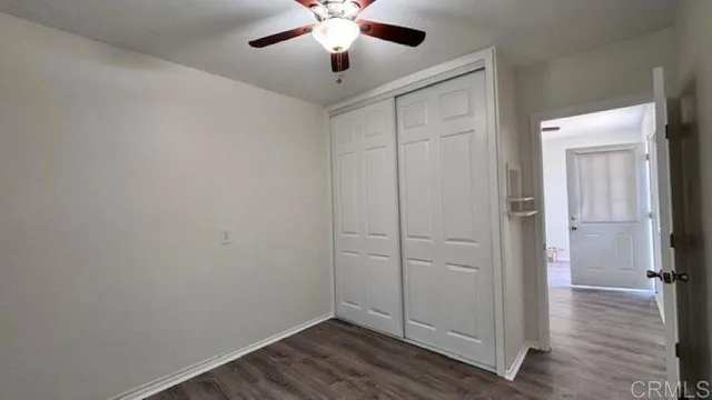 an empty room with wooden floor closet and ceiling fan