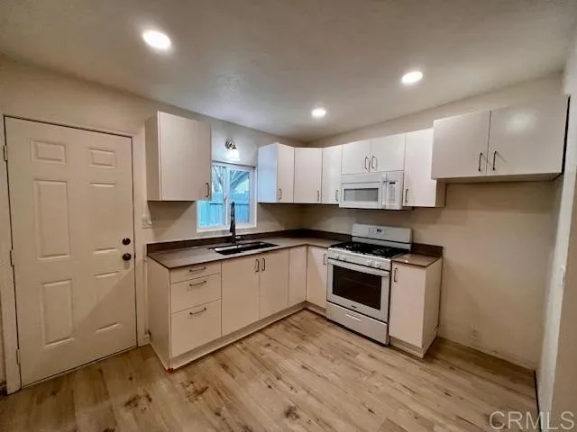 a kitchen with granite countertop white cabinets and appliances
