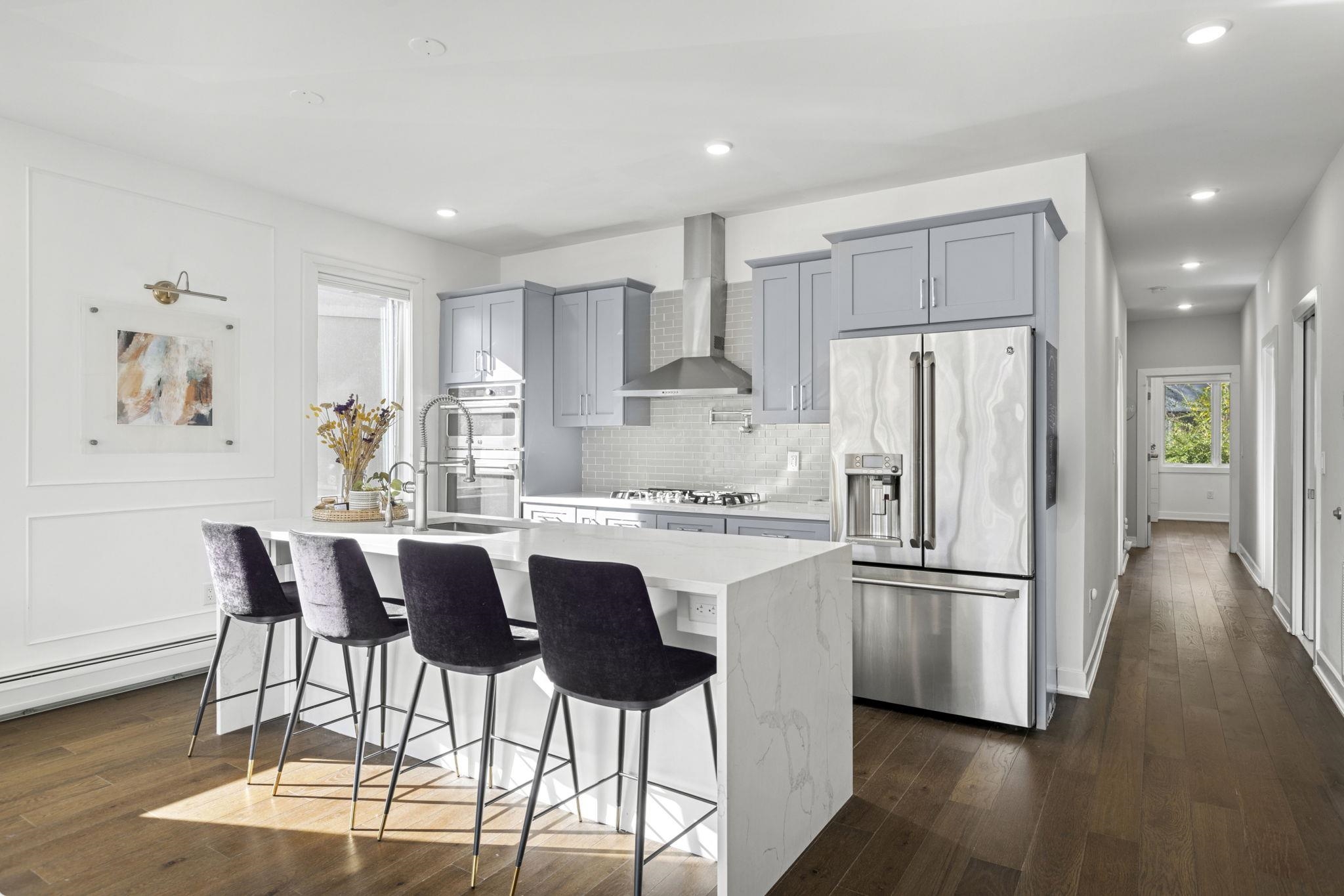 a kitchen with stainless steel appliances a dining table chairs refrigerator and cabinets