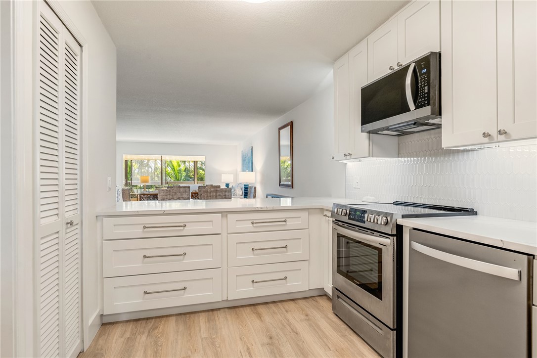 5101 Florida A1A, Unit 108 Vero Beach, FL 32963 - Photo 17 of 31 a kitchen with stainless steel appliances white cabinets and a stove top oven