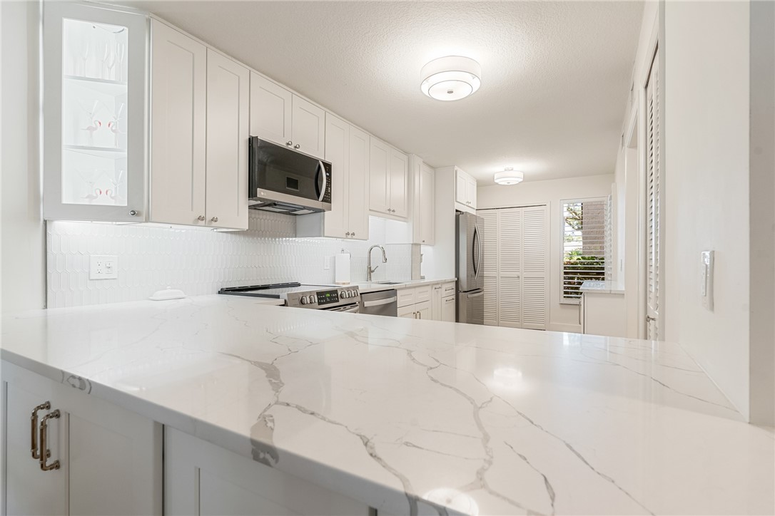 5101 Florida A1A, Unit 108 Vero Beach, FL 32963 - Photo 19 of 31 a kitchen with stainless steel appliances a stove top oven a sink a refrigerator and cabinets