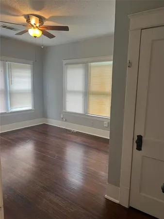 a view of empty room with wooden floor and fan