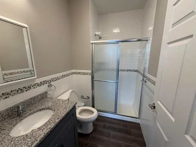 a bathroom with a granite countertop sink toilet and shower