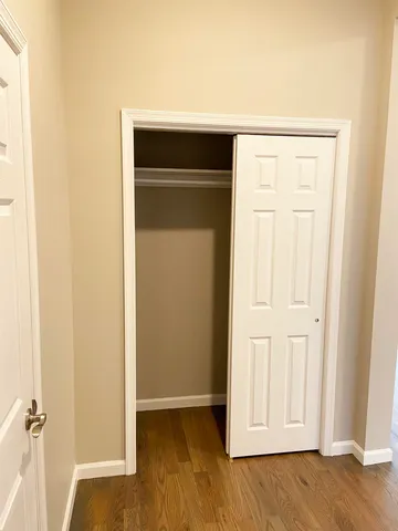 an empty room with wooden floor and closet area