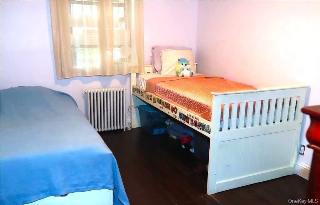 71-38 147th Street, Unit 27A Queens, NY 11367 - Photo 5 of 8 Bedroom featuring radiator heating unit and dark wood-style floors