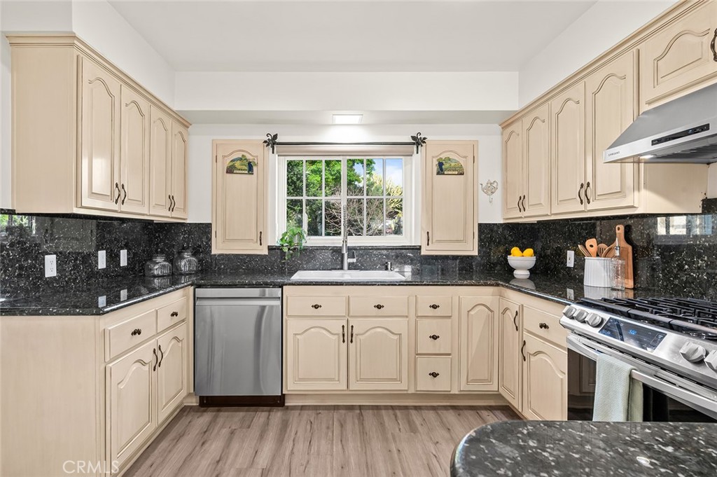 5487 Cadbury Road Whittier, CA 90601 - Photo 15 of 73 a white kitchen with granite countertop a stove top oven a sink dishwasher and white cabinets with wooden floor