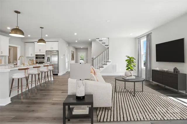 a living room with furniture a flat screen tv and kitchen view