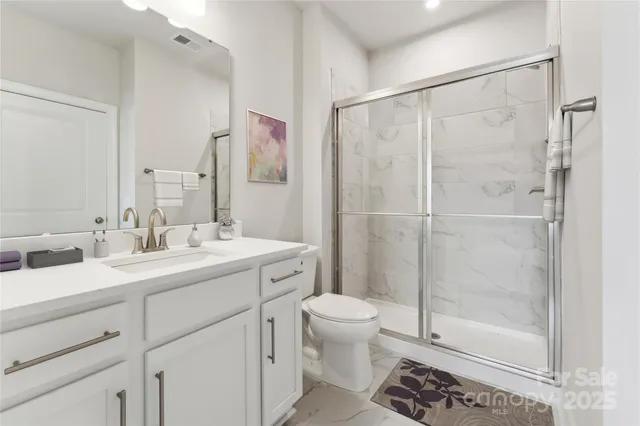 a bathroom with a shower sink vanity mirror and toilet