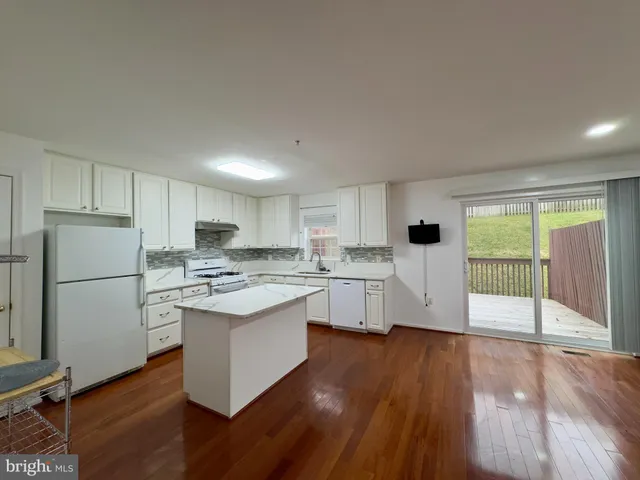 a living room with stainless steel appliances kitchen island hardwood floor sink and stove