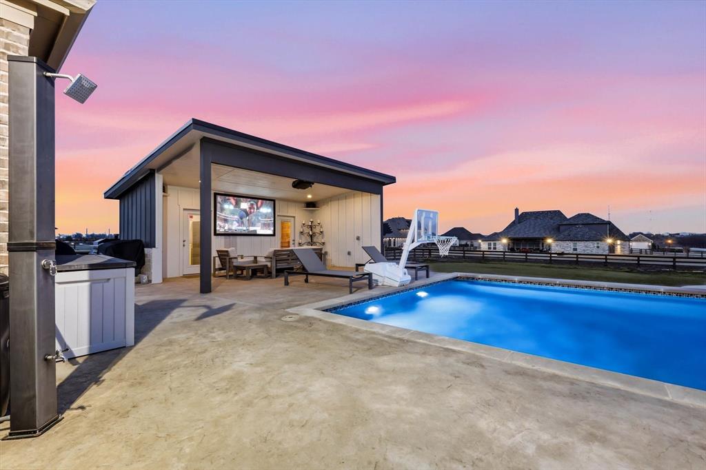 7751 Faught Road Northlake, TX 76226 - Photo 37 of 39 Outdoor living area featuring a rectangular swimming pool with integrated lighting, a pool house with a covered patio, an outdoor shower, and stamped concrete decking