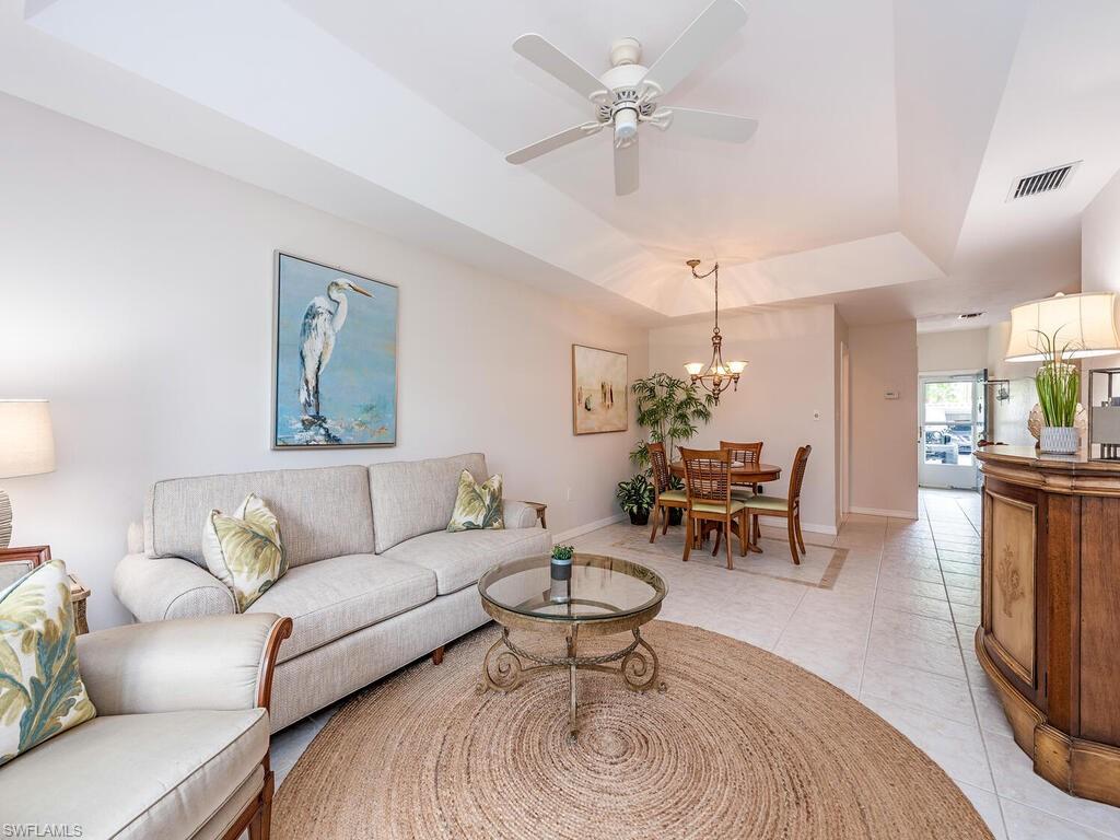 809 Augusta Boulevard, Unit 8092 Naples, FL 34113 - Photo 4 of 12 a living room with furniture a chandelier and a dining table