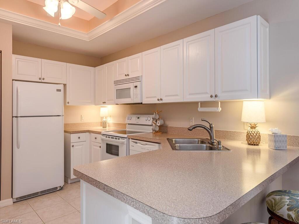 809 Augusta Boulevard, Unit 8092 Naples, FL 34113 - Photo 6 of 12 a kitchen with kitchen island a white counter top space cabinets and stainless steel appliances