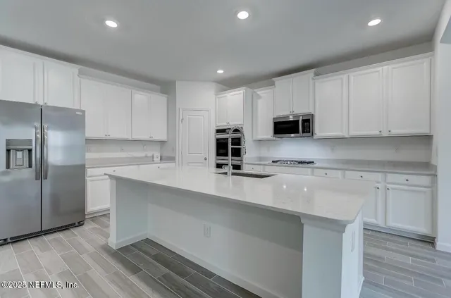 a kitchen with kitchen island a sink stainless steel appliances and white cabinets