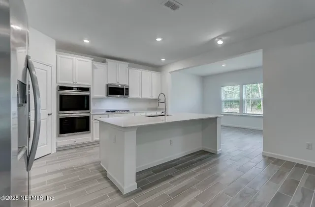 a kitchen with white cabinets and stainless steel appliances
