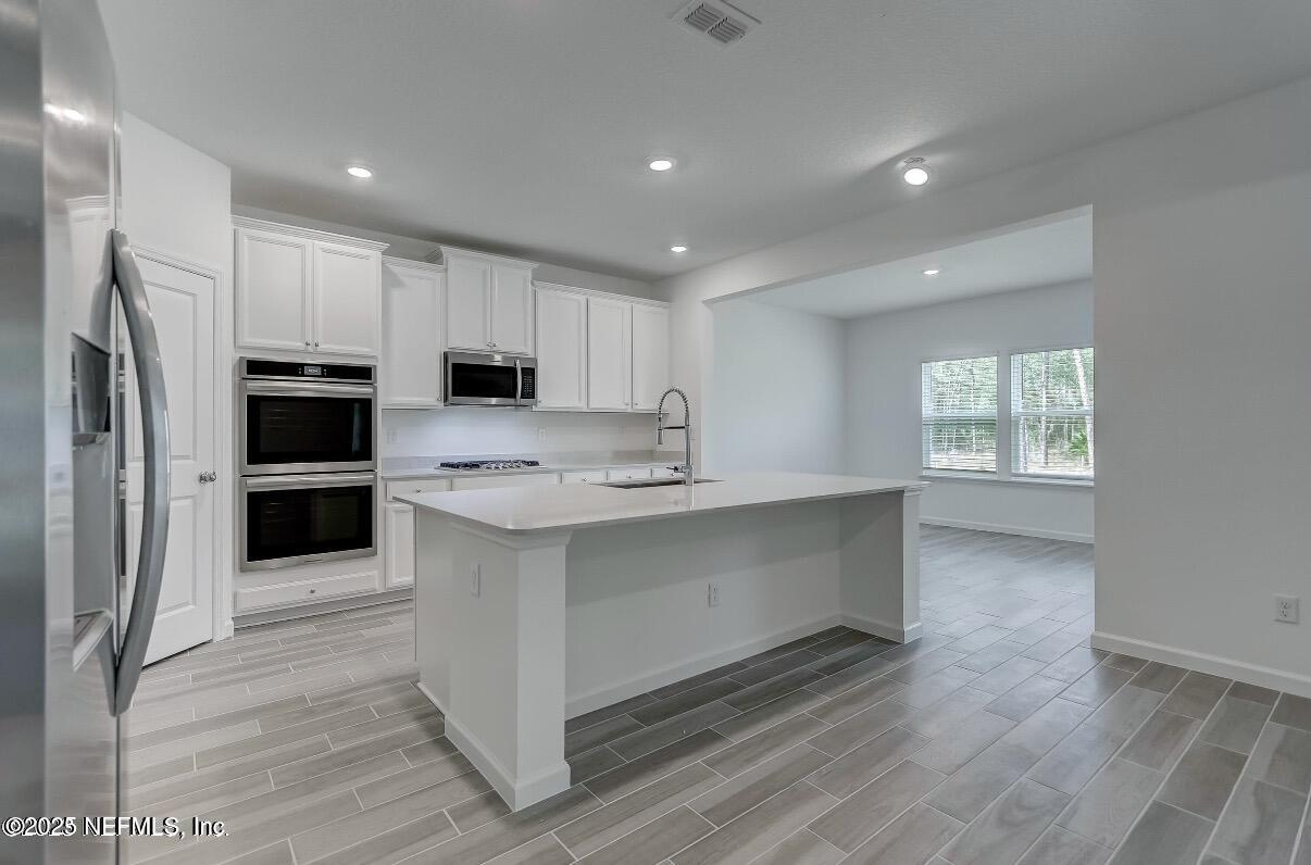 300 Gan Way St. Johns, FL 32259 - Photo 12 of 36 a kitchen with white cabinets and stainless steel appliances
